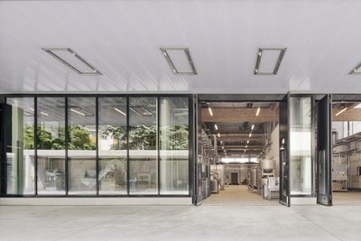 This architectural image showcases a modern industrial building with a striking glass facade and fol