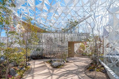 The image showcases a modern pavilion with a striking geometric steel frame and glass facade. The st