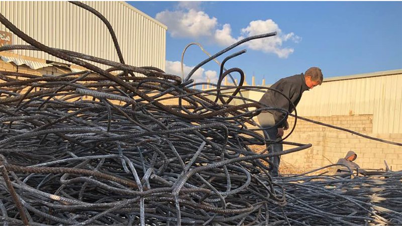 Locals collecting and sorting reclaimed steel, transforming debris into structural material for community-led rebuilding.