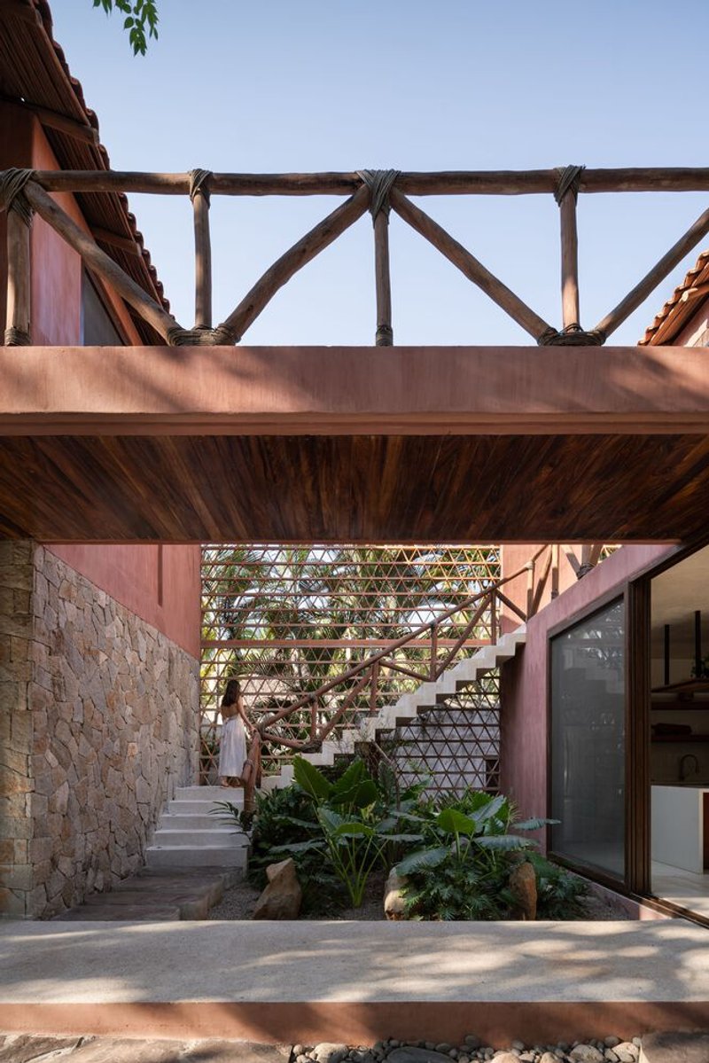 Courtyard view of the timber-framed bridge and open stair connecting upper and lower levels with planted beds below