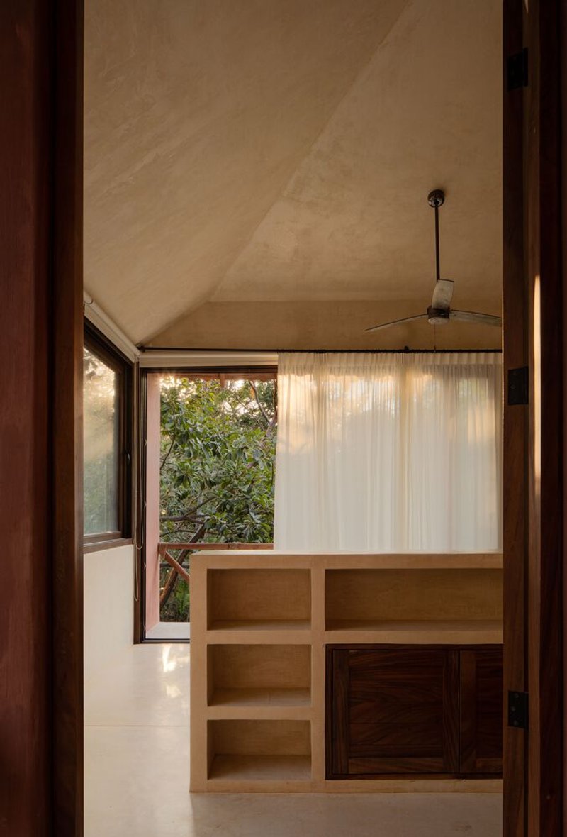 Interior room with built-in shelving and a translucent curtain beneath a vaulted plaster ceiling