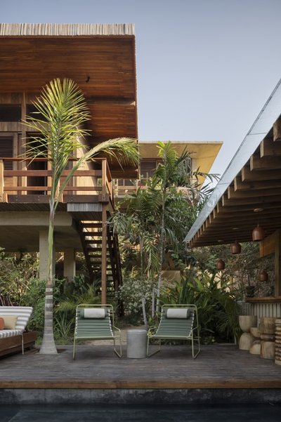 This architectural image showcases a tropical-style house with a wooden deck and outdoor lounge area