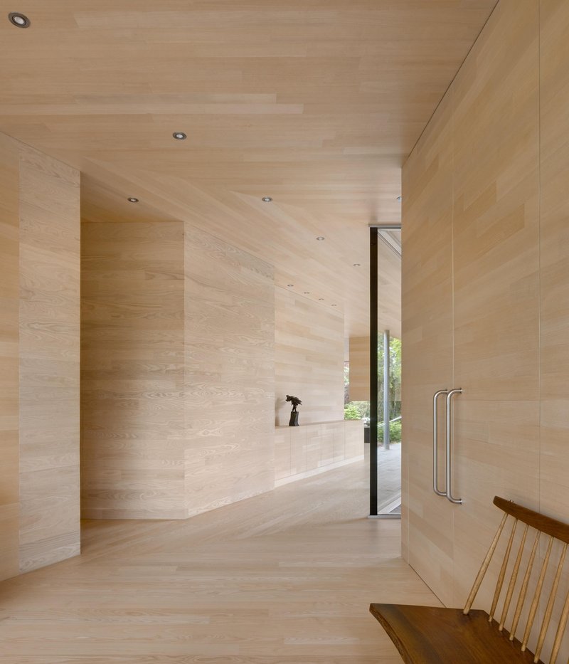 Light-toned wood-clad entry hallway with recessed lighting and glazed door to exterior garden