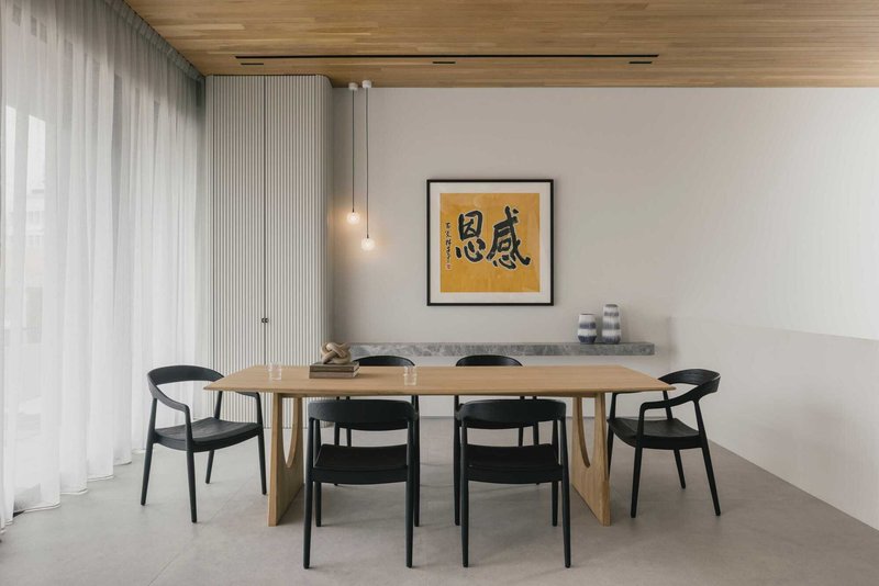 Dining area with timber table, black chairs and vertical slatted wall beneath a timber ceiling