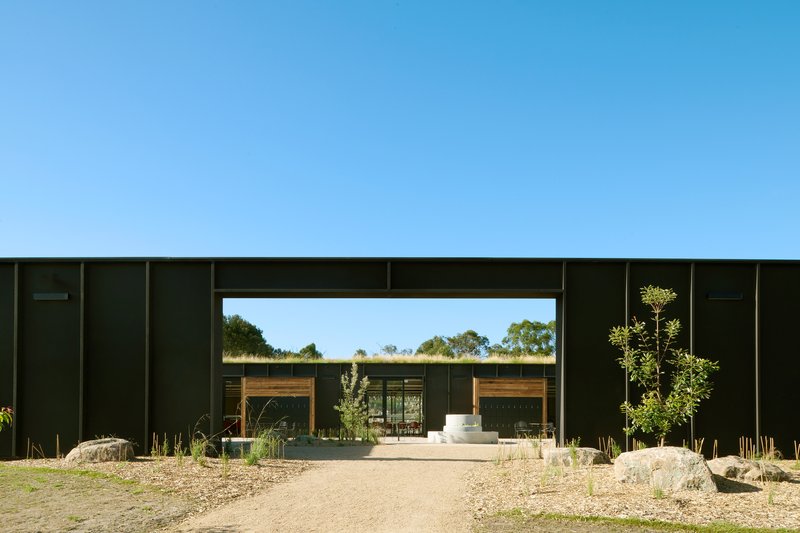 Main entry framed by a tall rectangular opening cut through the dark boarded facade