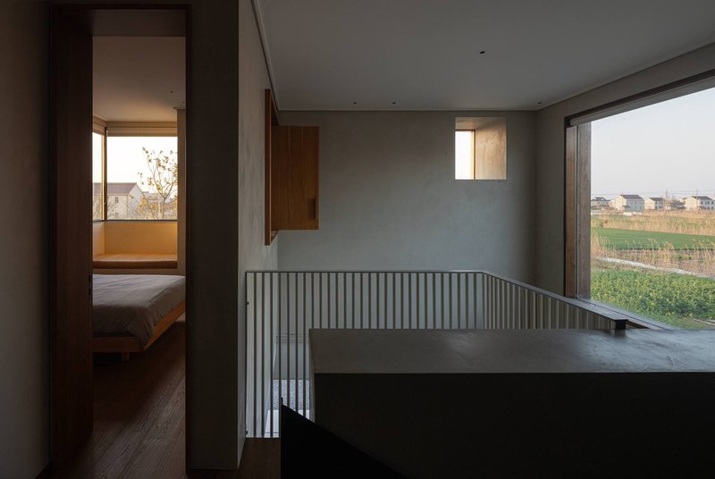 Upper landing with vertical slat railing opening to bedroom and large windows framing rural landscape