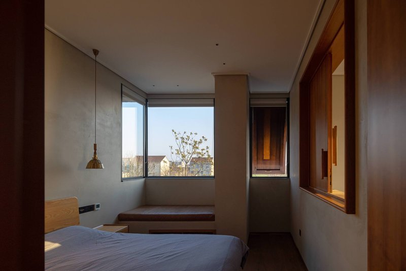 Bedroom with corner windows, timber built-in desk and pendant light in afternoon sun