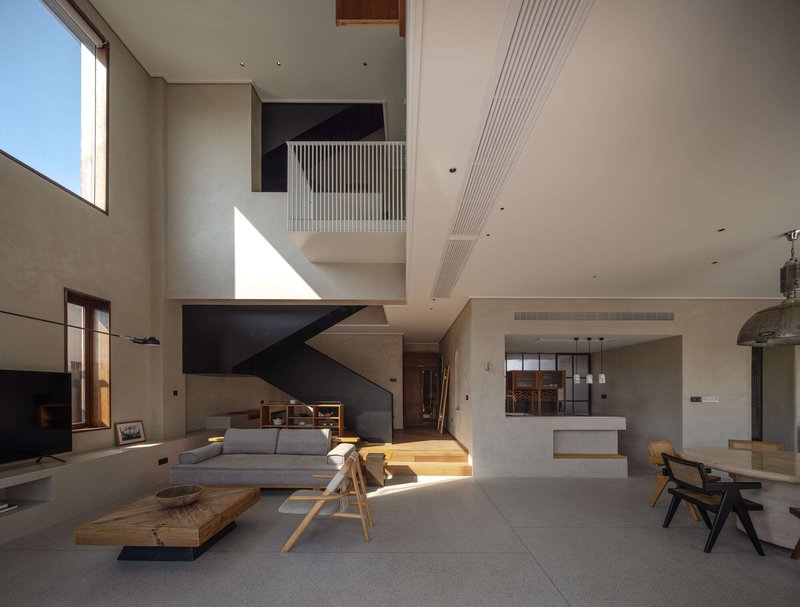 Double-height living space with black steel stair and sunlight streaming through high clerestory window