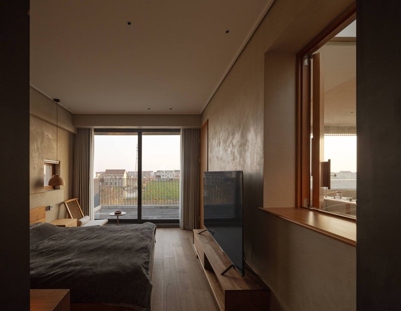 Bedroom with timber-framed window alcove overlooking fields and an ensuite bathroom beyond