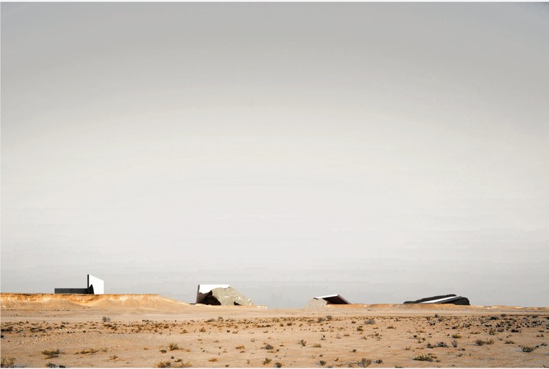 A distant view of the intervention situates the project within the vast desert, emphasizing contrast between minimal architecture and expansive landscape.