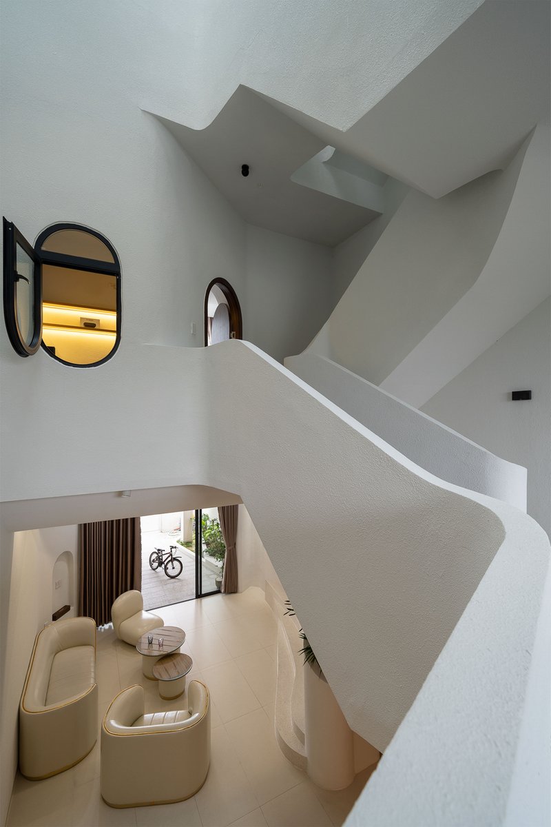 Double-height living room with spiral staircase and arched mirrors overlooking beige seating