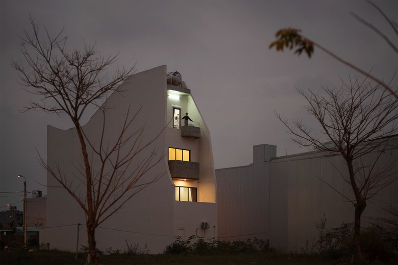 Rear elevation at night showing stacked illuminated openings between bare winter trees