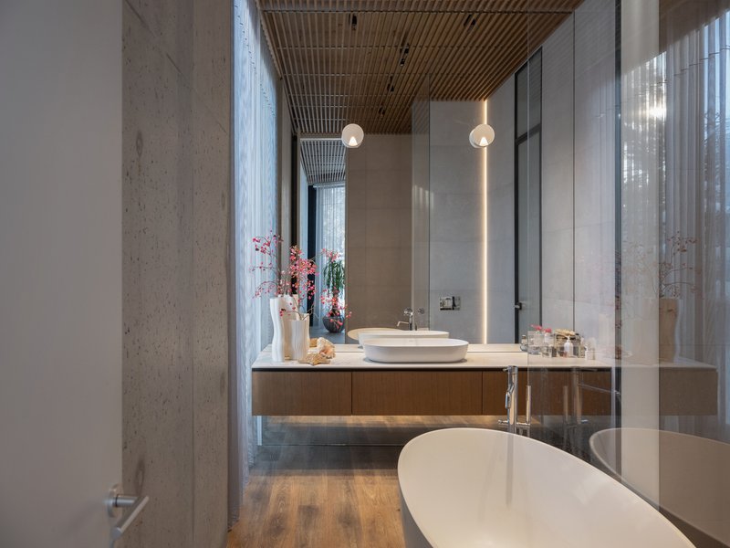 Bathroom with floating timber vanity, freestanding white tub, and concrete columns beside sheer drapes
