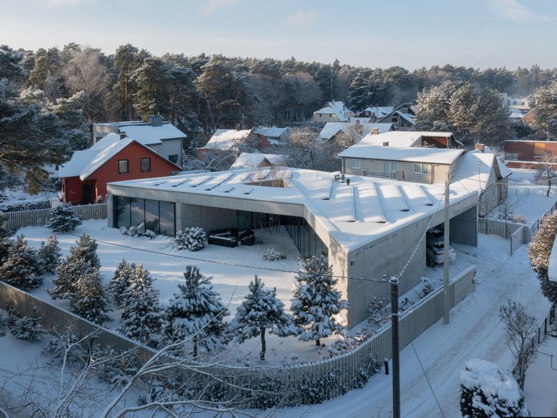 Aerial view of the triangular roof geometry nestled in a snow-covered residential neighborhood with pine trees
