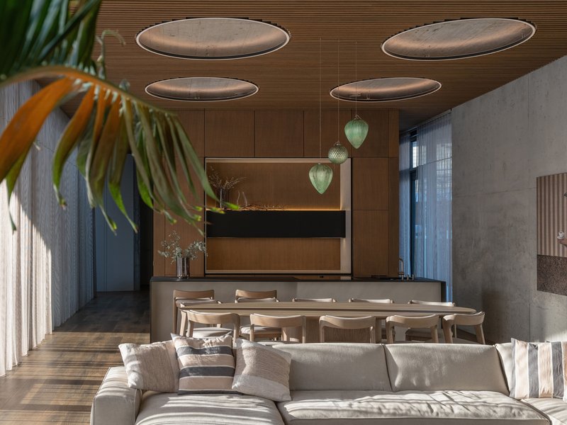 Combined dining and living area with circular acoustic panels suspended below a timber ceiling
