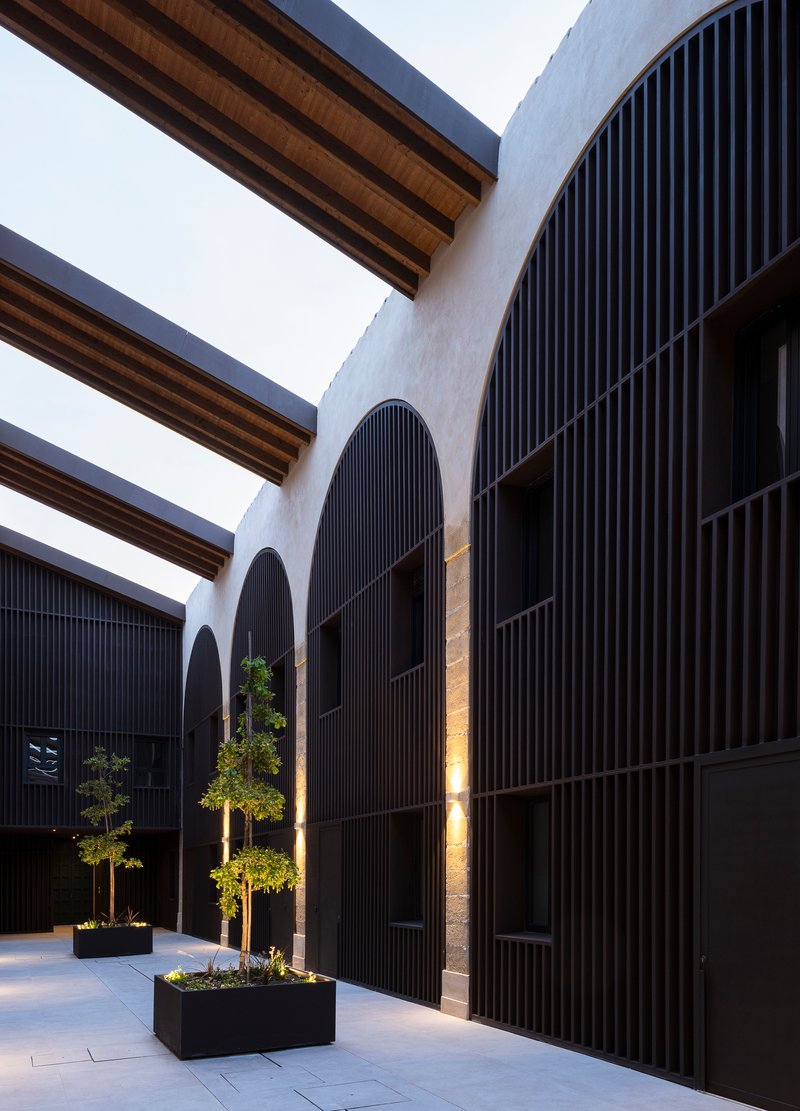 Arcaded courtyard with timber roof beams and dark slatted wall panels