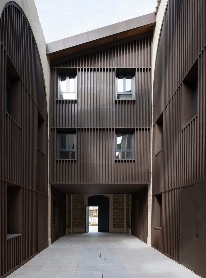 Internal alley culminating in a tall residential facade above a passage