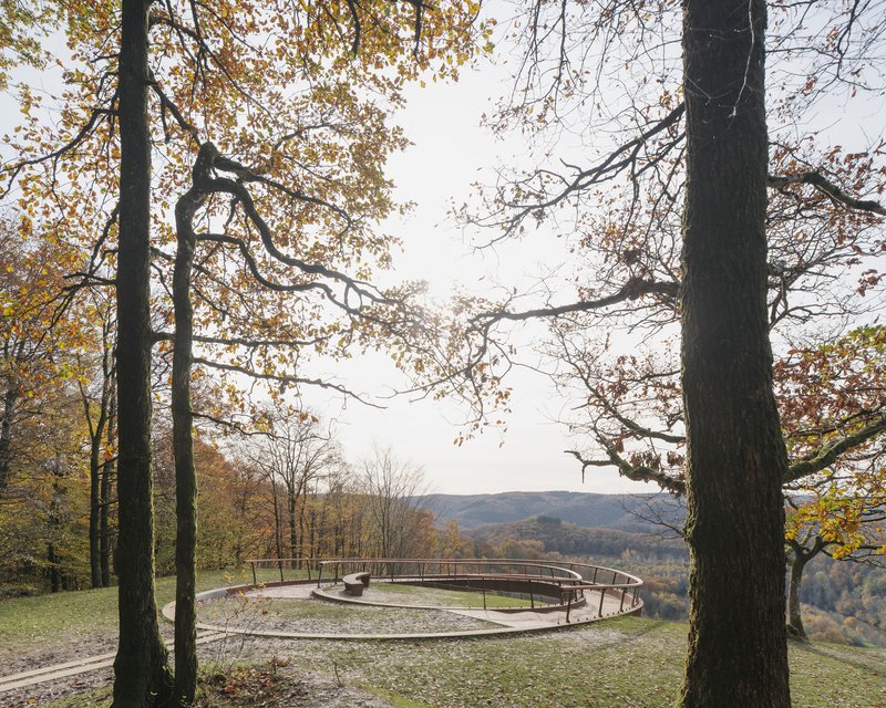 The circular weathering steel walkway sitting on the hilltop framed by oaks