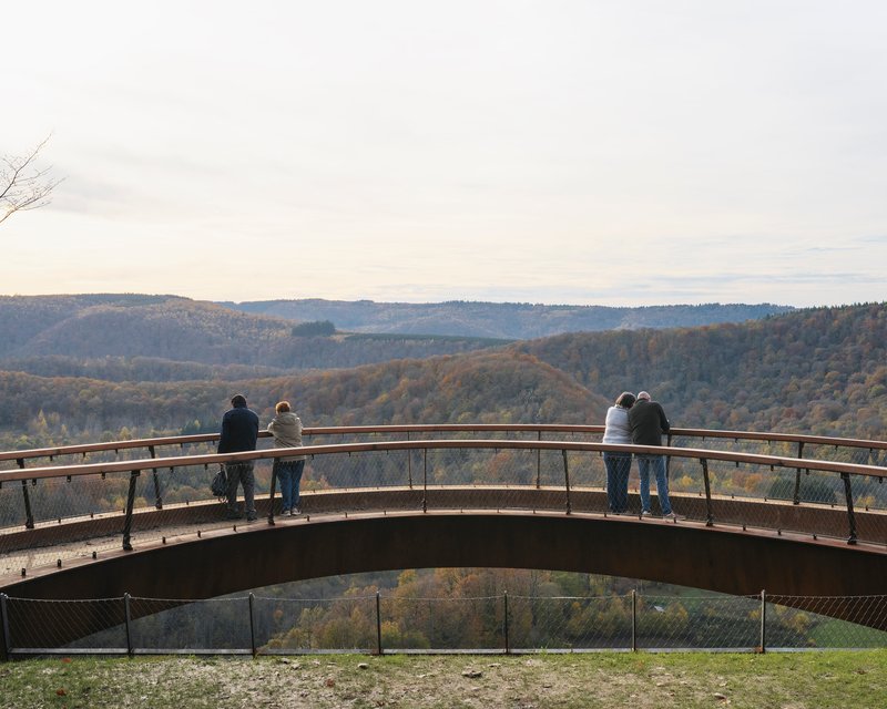 Couples leaning over the railing of the curving walkway at sunset