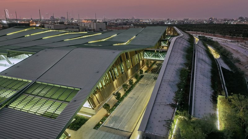 Aerial view of the illuminated central plaza flanked by green roofs at twilight