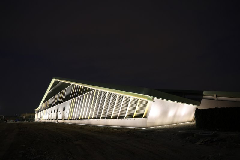 Corner view of the angular volume with vertical white fins and uplighting at night