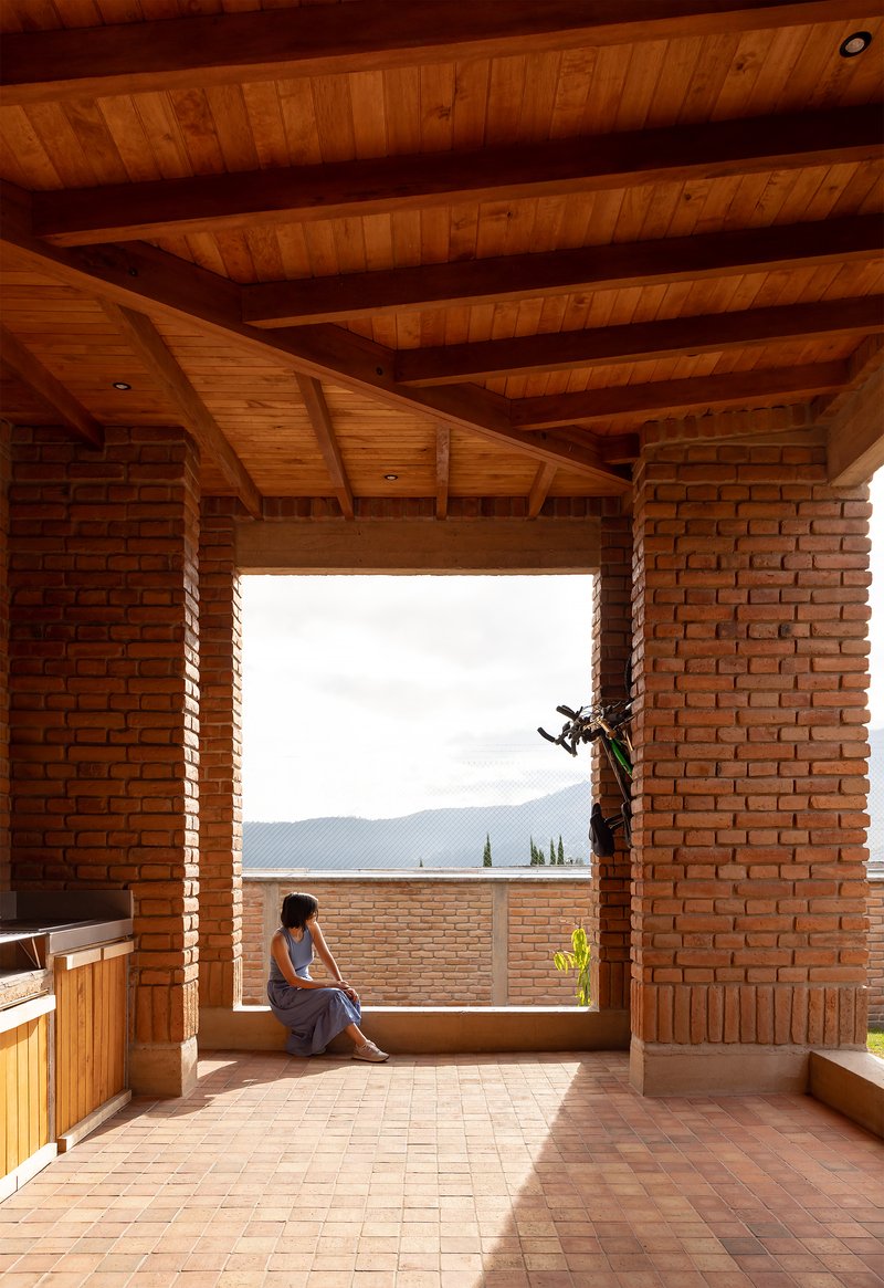 Window seat framed by brick piers and timber ceiling with a mountain view beyond