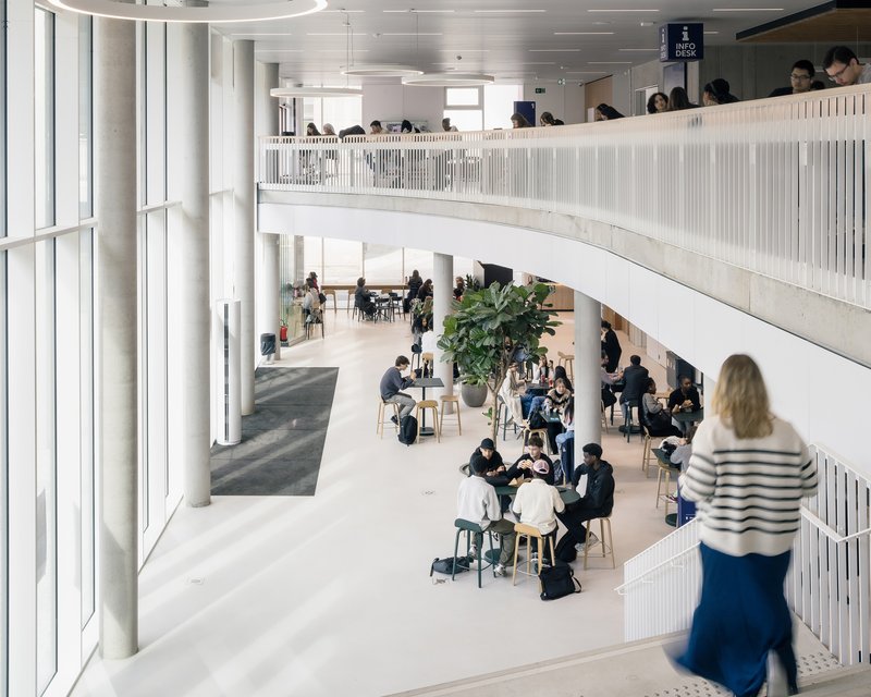Double-height central atrium with cafe seating and the curved upper gallery
