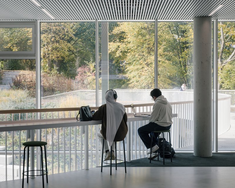 Two students working at a window counter overlooking the planted terrace