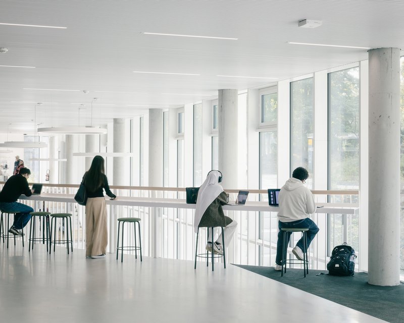 Upper-level study counter with bar stools along a fully glazed wall