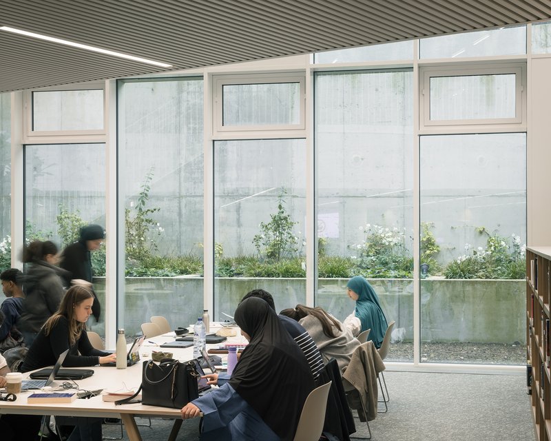 Group study tables along the glazed wall facing the planted courtyard