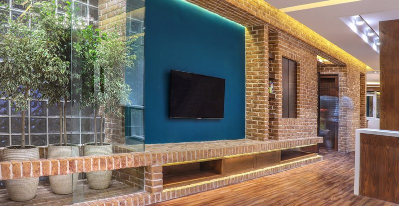 Integrated greenery and glass soften the brick interior, enhancing light and spatial depth.