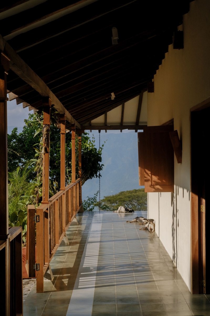 Covered walkway with exposed timber rafters, tiled floor, and view to distant water