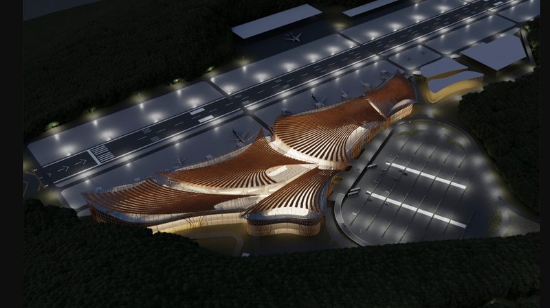 Aerial night view revealing organic roof geometry and integrated site planning with runway and parking.