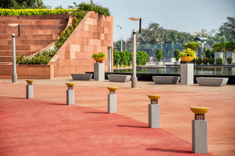 Outdoor terrace with stepped sandstone seating and short concrete bollards topped with golden discs