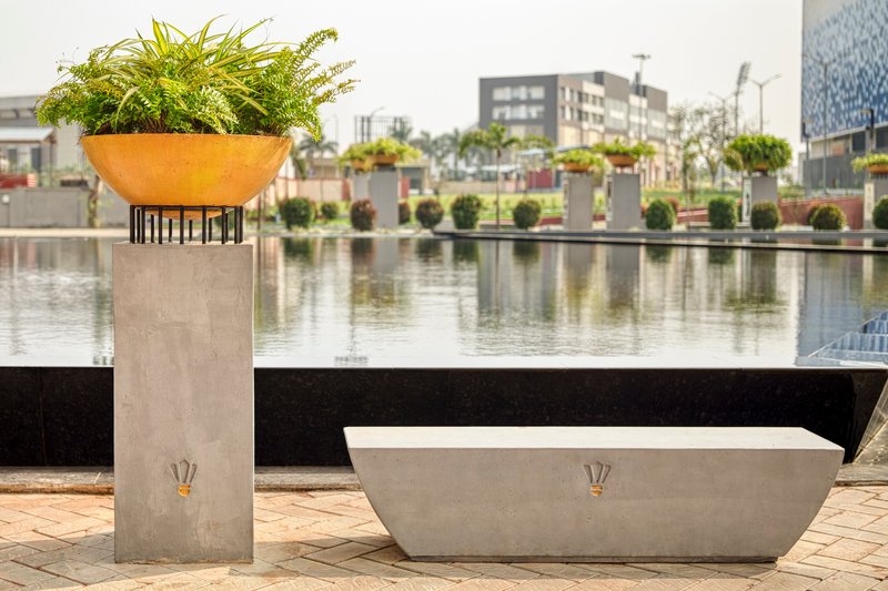 Concrete planter column and seating bench beside a reflecting pool with distant buildings