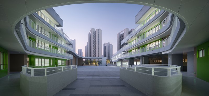 View through an elliptical courtyard opening toward high-rise towers at dusk