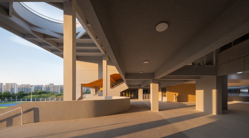 Covered outdoor terrace with concrete columns and coffered ceiling illuminated by golden hour sunlight