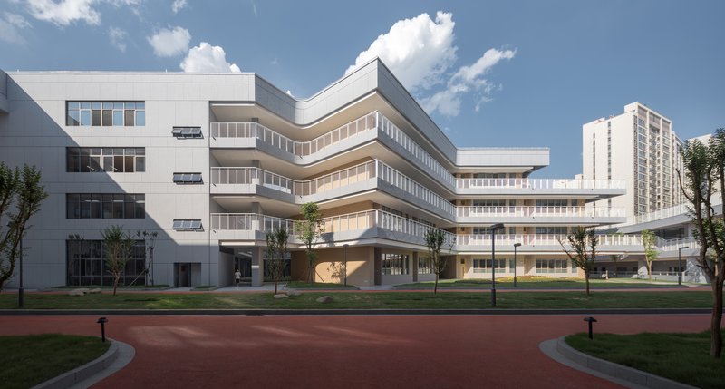 Stacked horizontal facade with continuous ribbon windows overlooking a landscaped lawn and running track