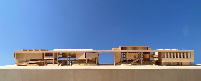 Section model showing layered horizontal volumes with timber screens and central courtyards cutting through the mass