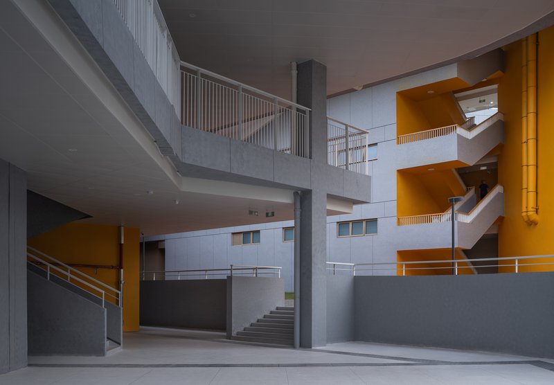 Interior atrium with multilevel gray balconies and orange soffit accents at dusk