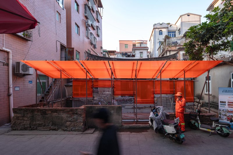 Orange tensile canopy structure with metal frame in a residential courtyard at dusk