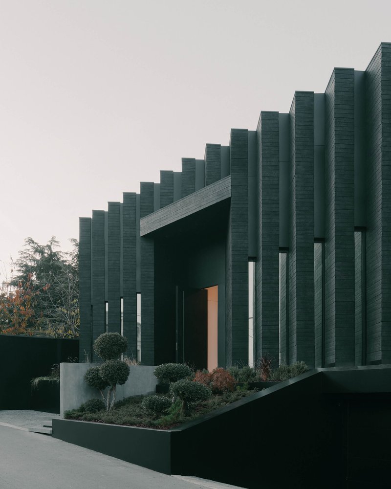 Street view of the vertical fin facade with planted beds at dusk