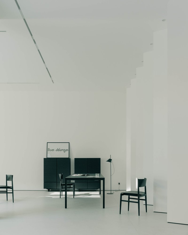 Double-height living space with dark green furniture and artwork on white polished floor