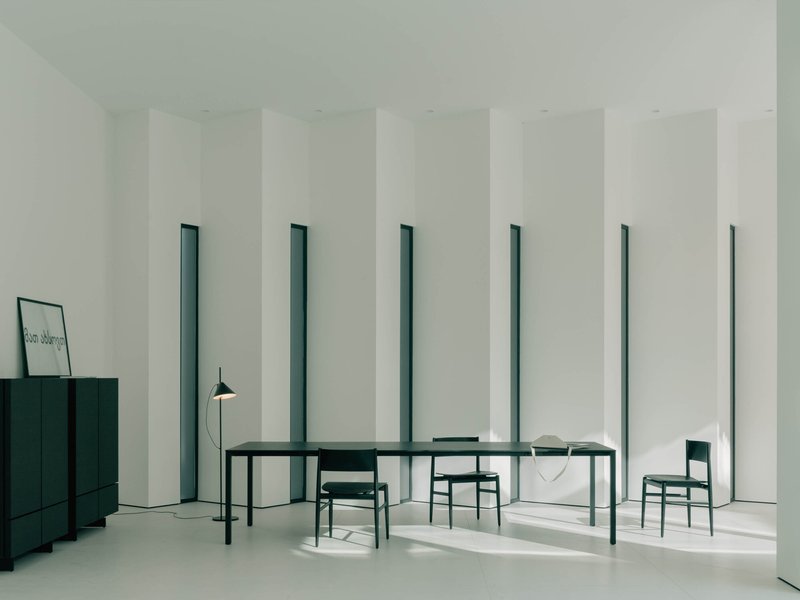 Dining room with rhythmic vertical window slots framing dark green table and chairs