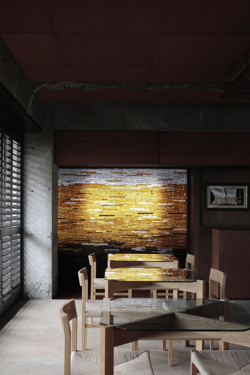 Dining area with backlit horizontal timber screen wall illuminating the seating area at dusk
