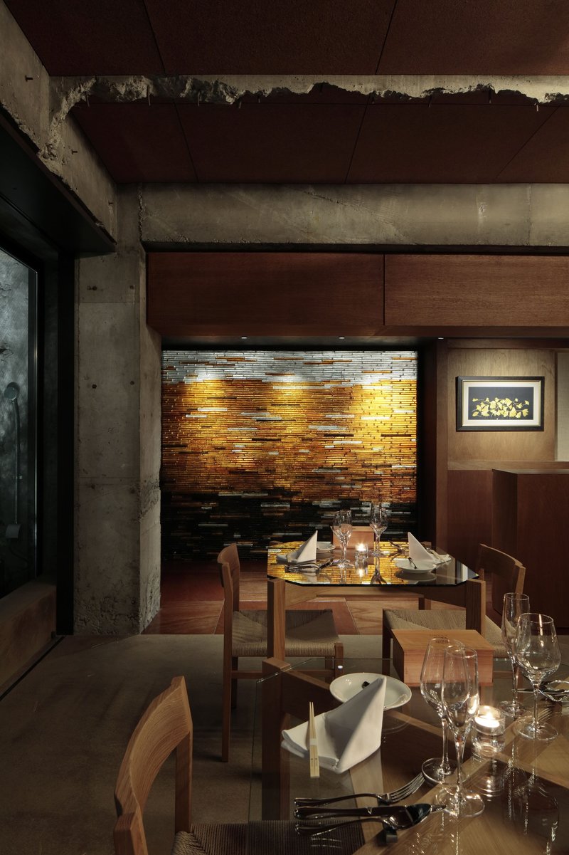 Dining area featuring copper tile accent wall and exposed concrete beam with candlelit tables