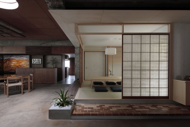 Translucent shoji screen partitions enclosing a tatami room with cushions, viewed from the dining area