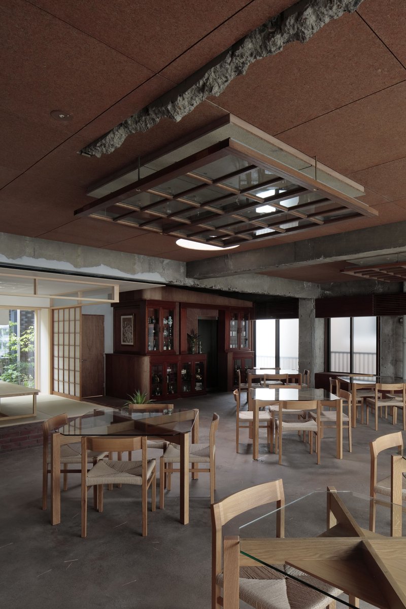 Open dining space with wooden furniture under suspended lattice light fixture and brown paneled ceiling