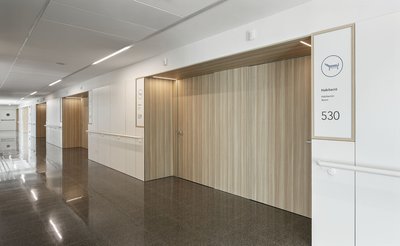 This architectural image showcases a modern hospital corridor with a minimalist design. The space fe