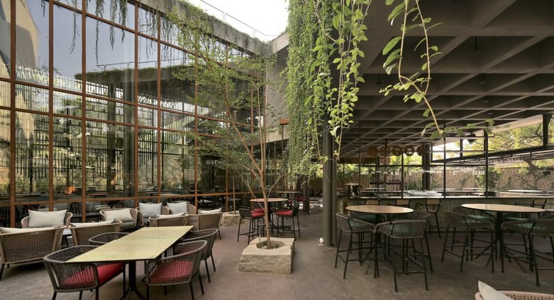 Double-height courtyard with planters and glazed facade beneath an exposed concrete waffle slab